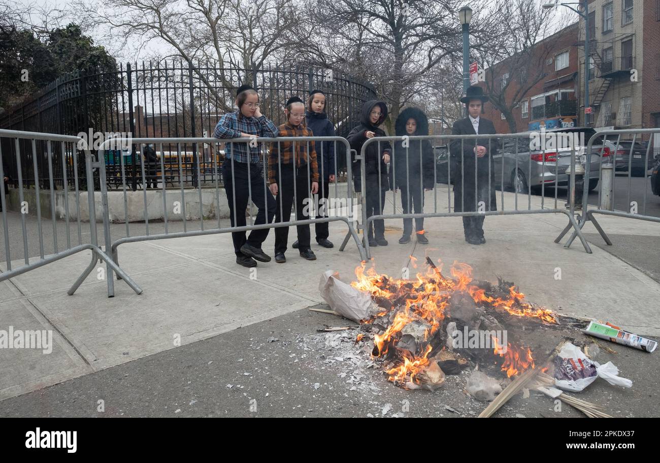 Eine kleine Gruppe chassidischer jüdischer Jungen ist die erste, die zu einem Lagerfeuer kommt, um Brotprodukte zu verbrennen, Stunden vor dem Start des Passahs. In Brooklyn, New York City. Stockfoto