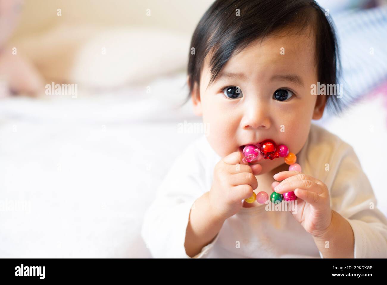 Baby mit Spielzeug im Mund Stockfoto