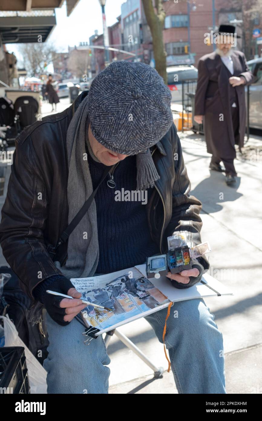 Ein jüdischer Mann mit Mütze malt Bilder vom jüdischen Leben auf der Lee Avenue in Williamsburg, kurz vor dem Passover 2023. In Brooklyn, New York. Stockfoto