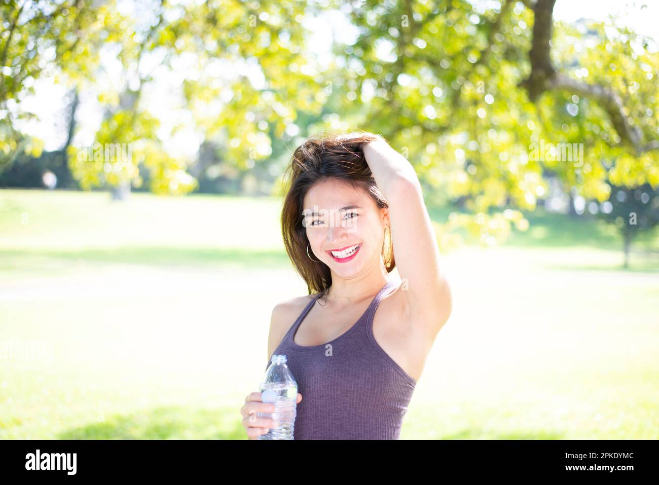 Eine Frau, die im Park mit einer Wasserflasche lacht Stockfoto