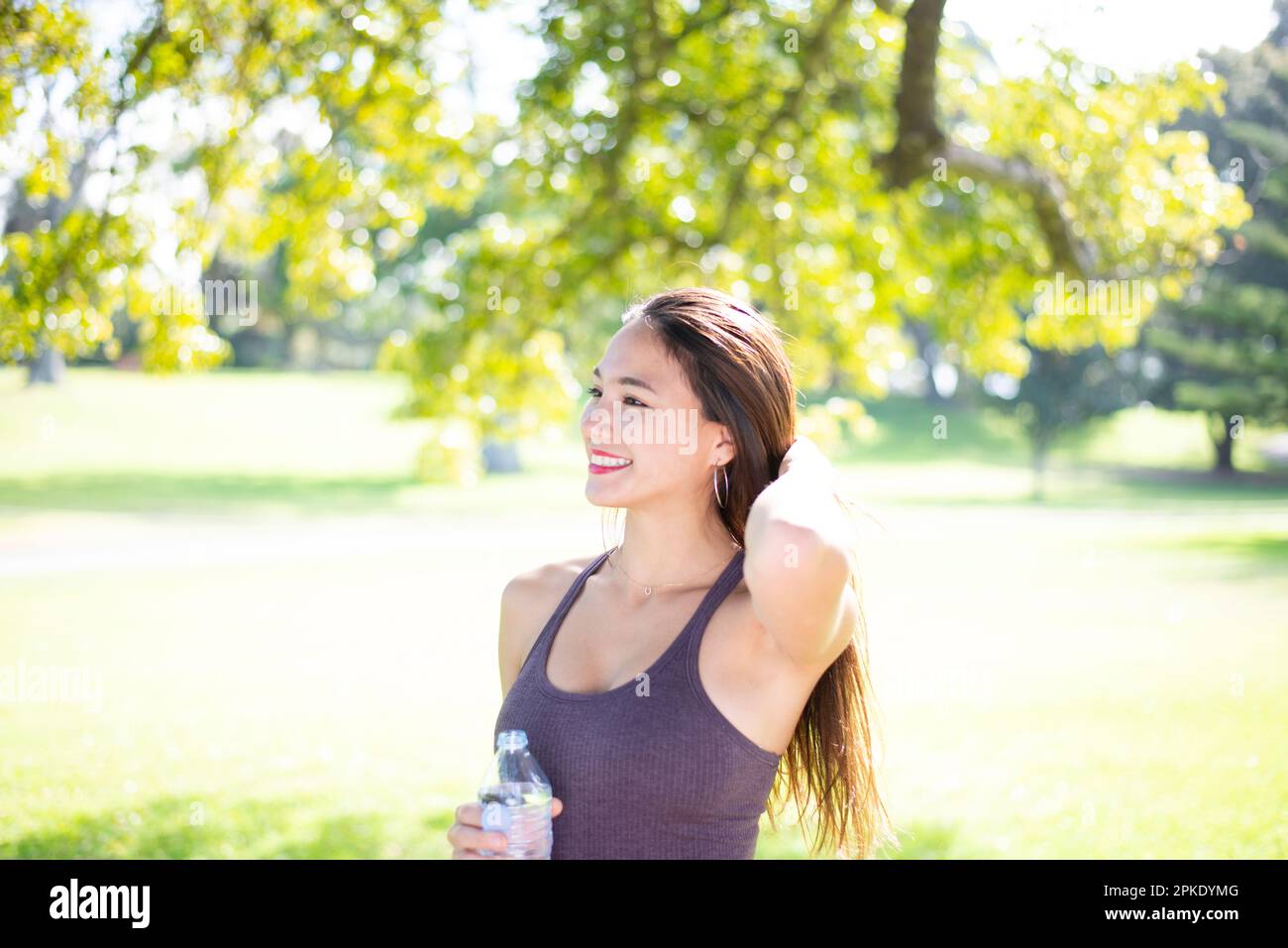 Eine Frau, die im Park mit einer Wasserflasche lacht Stockfoto