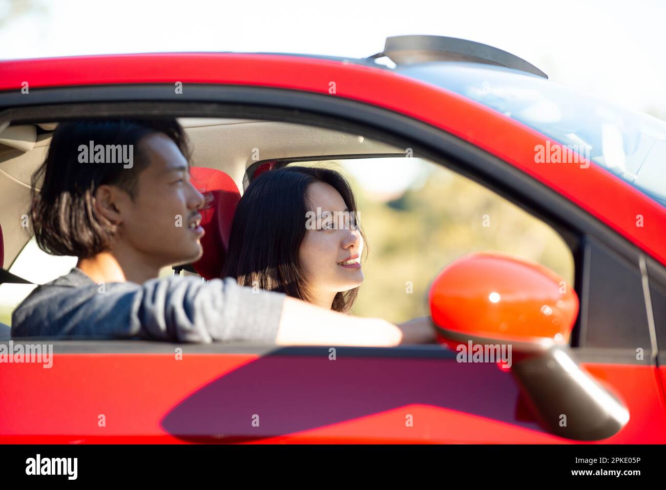 Mann und Frau, die im roten Auto fahren Stockfoto