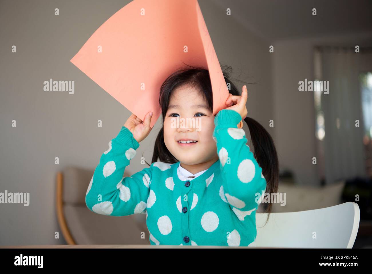 Ein Mädchen, das ein Zeichenpapier auf dem Kopf hält Stockfoto
