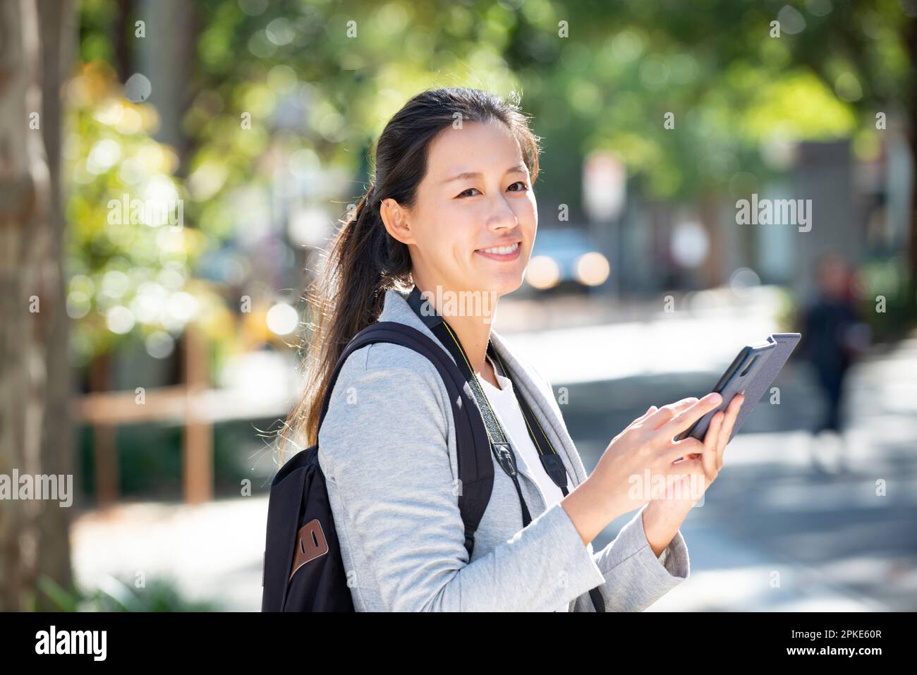 Eine Frau, die ein Smartphone an einer Straßenecke hält Stockfoto