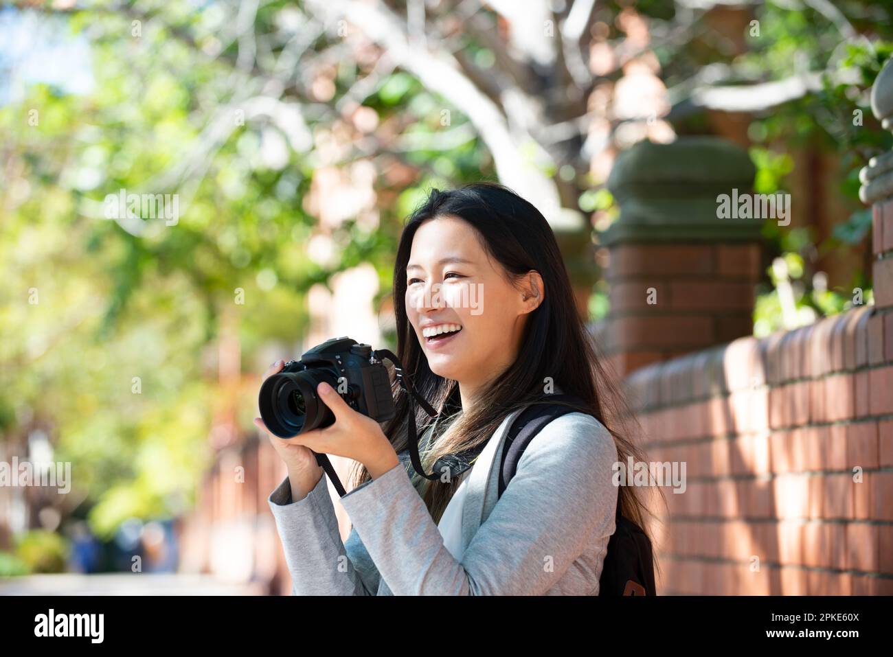 Eine Frau, die eine Spiegelreflexkamera hält und lacht Stockfoto