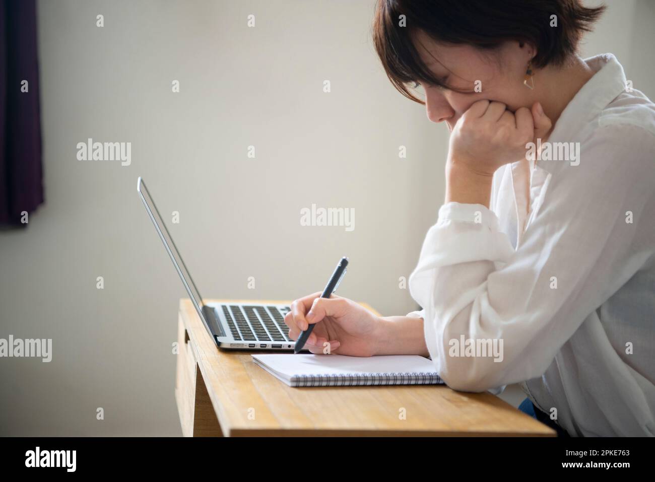 Frau, die sich neben einem Computer Notizen macht Stockfoto