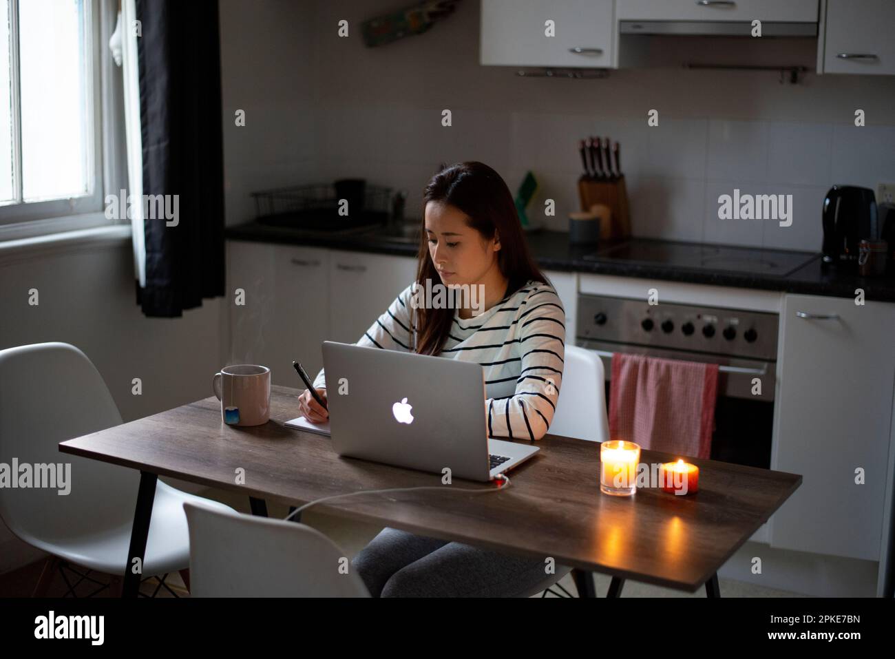 Frau, die an einem Computer in einer Küche arbeitet Stockfoto