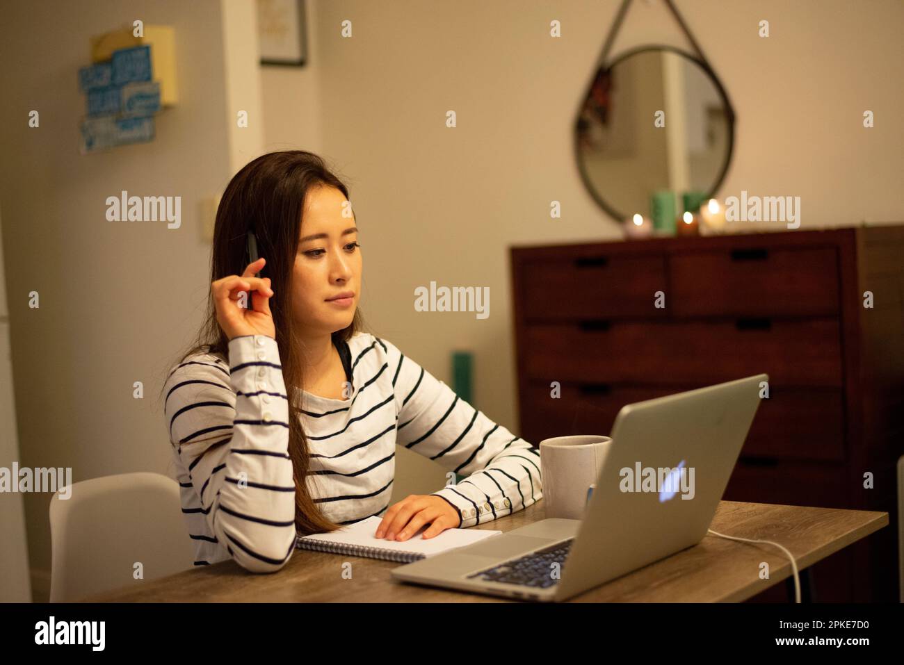 Eine Frau, die zu Hause vor einem Computer denkt Stockfoto