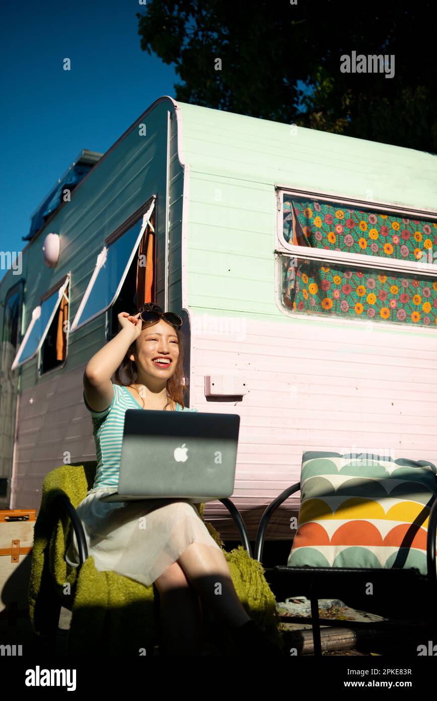 Frau, die den Computer vor dem Campingwagen bedient Stockfoto