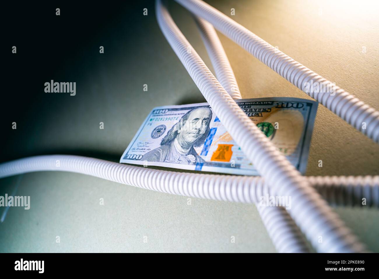 Welldraht und Nahaufnahme von Bargeld. Graues Wellrohr für elektrische Drähte und hundert Dollar Stockfoto