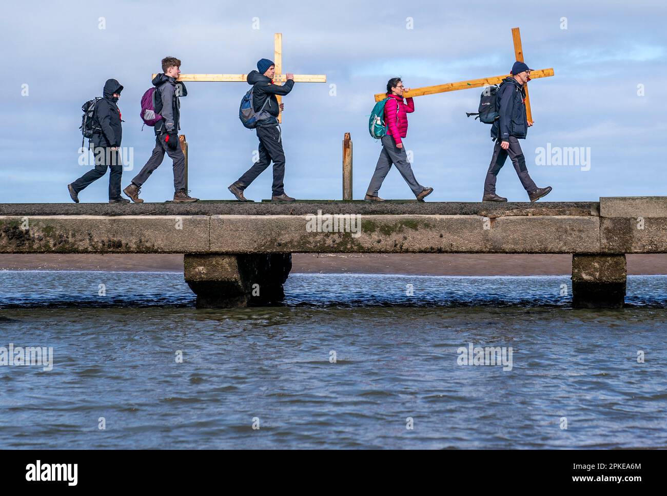 Pilger, die Kreuze zur Heiligen Insel Lindisfarne in Northumberland transportieren, während der jährlichen christlichen Osterpilgerfahrt am Karfreitag. Foto: Freitag, 7. April 2023. Stockfoto
