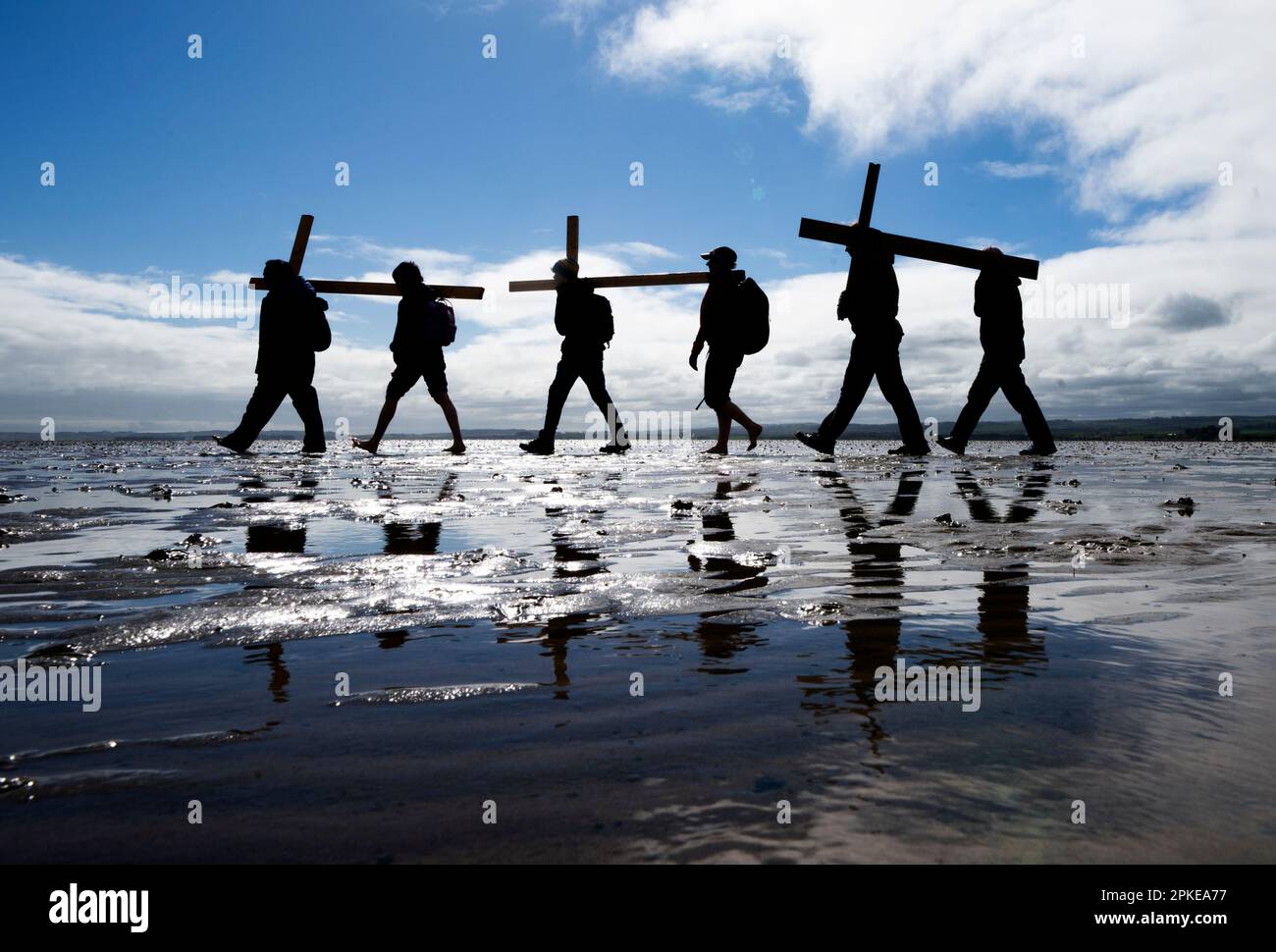 Pilger, die Kreuze über den Sand zur Heiligen Insel Lindisfarne in Northumberland transportieren, während der jährlichen christlichen Osterpilgerfahrt am Karfreitag. Foto: Freitag, 7. April 2023. Stockfoto