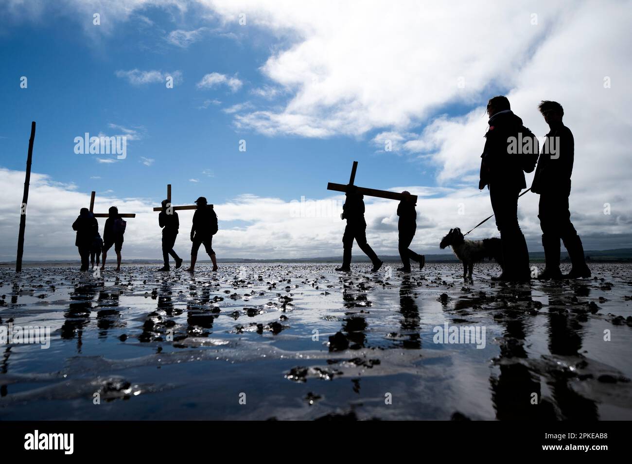 Pilger, die Kreuze über den Sand zur Heiligen Insel Lindisfarne in Northumberland transportieren, während der jährlichen christlichen Osterpilgerfahrt am Karfreitag. Foto: Freitag, 7. April 2023. Stockfoto