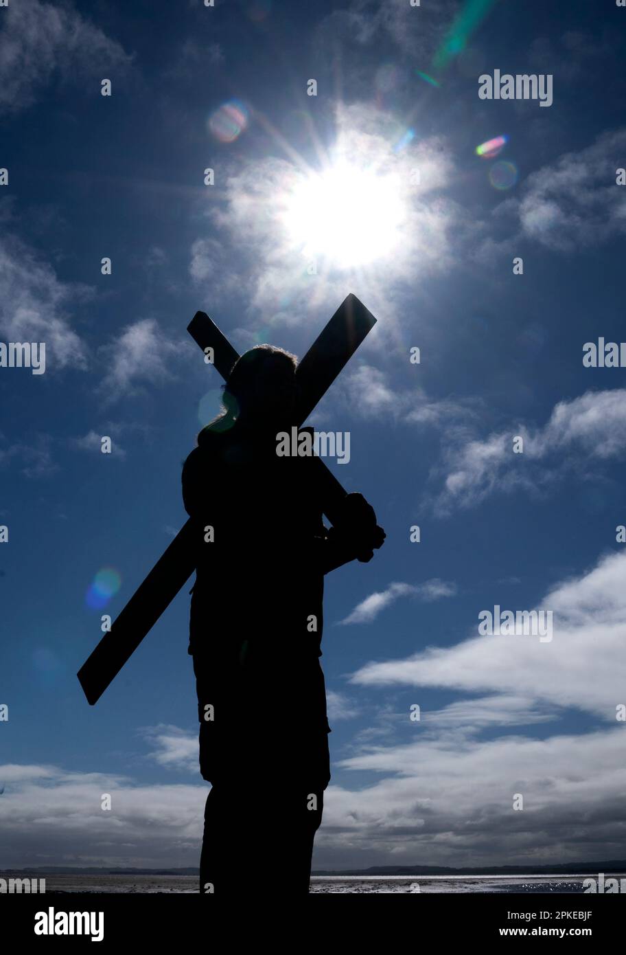 Ein Pilger am Anfang des Dammes, bevor er sein Kreuz auf die Heilige Insel Lindisfarne in Northumberland während der jährlichen christlichen Osterpilgerfahrt am Karfreitag trug. Foto: Freitag, 7. April 2023. Stockfoto