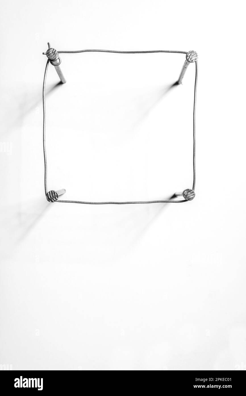 Der minimalistische Hintergrund des Eisendrahts bildet ein Quadrat auf weißem Hintergrund Stockfoto