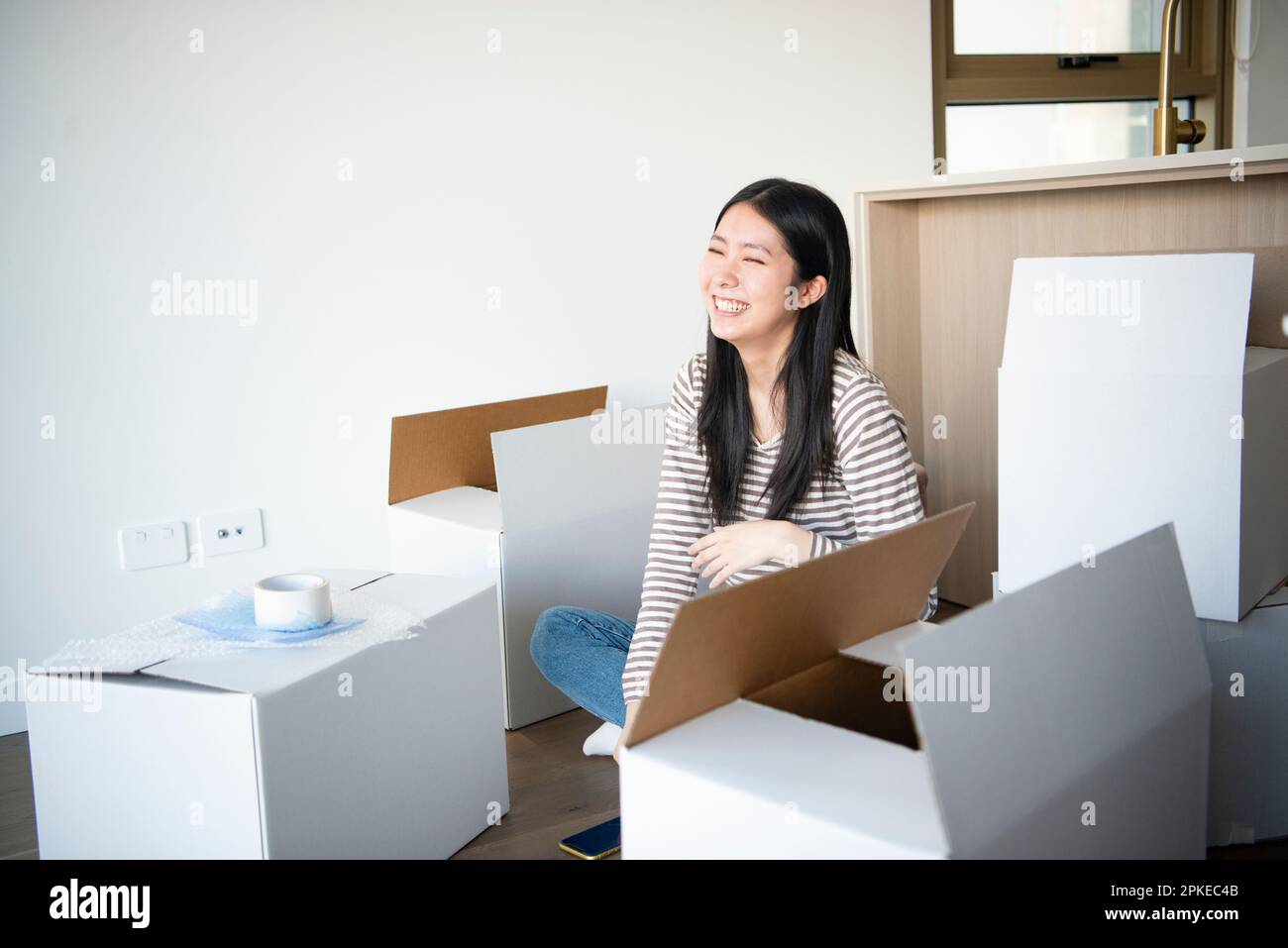 Lächelnde Frau, umgeben von beweglichem Karton Stockfoto