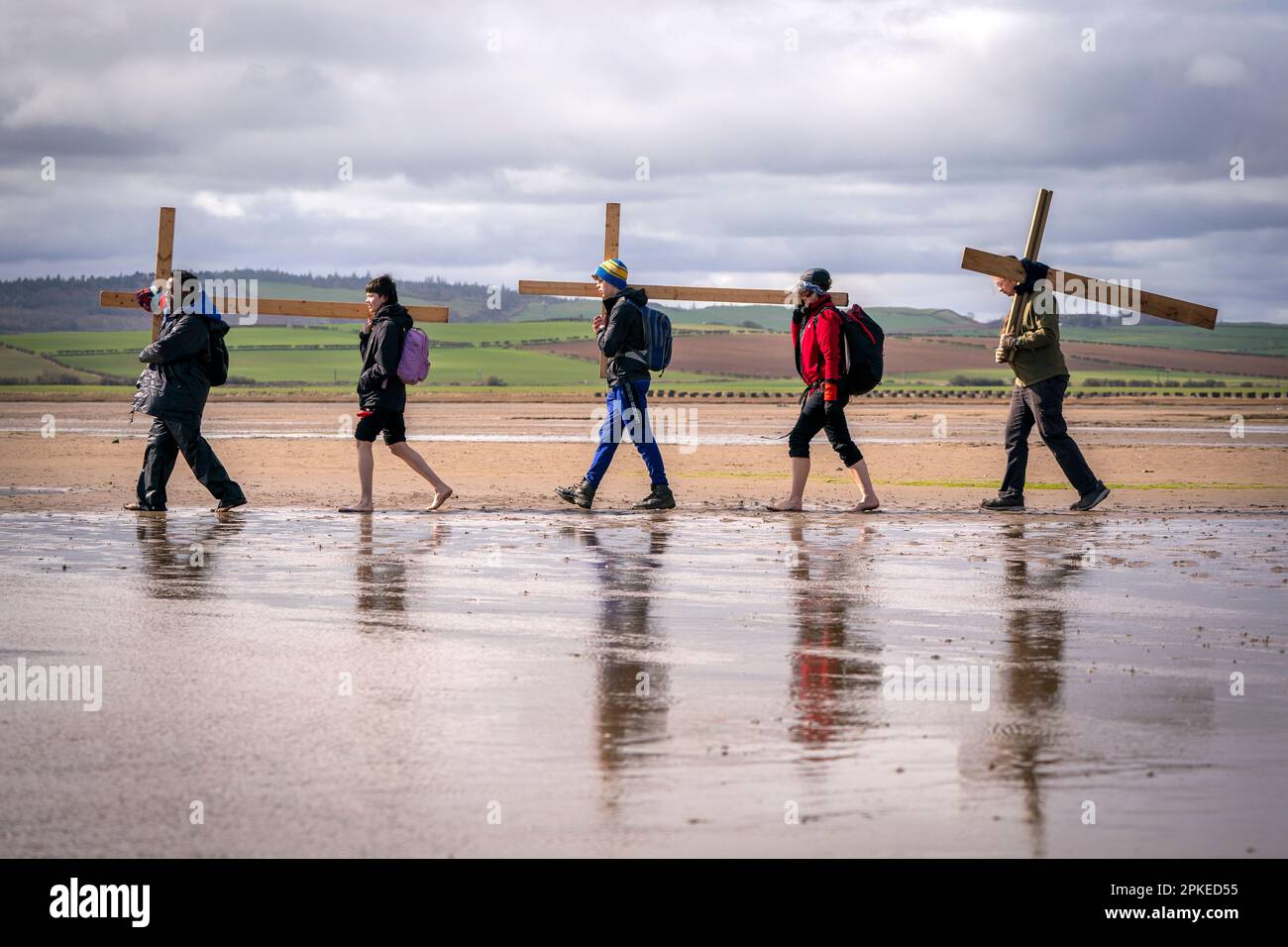 Pilger, die Kreuze zur Heiligen Insel Lindisfarne in Northumberland transportieren, während der jährlichen christlichen Osterpilgerfahrt am Karfreitag. Foto: Freitag, 7. April 2023. Stockfoto