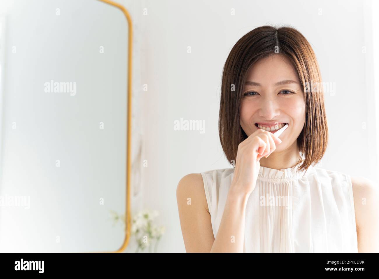 Eine Frau, die beim Zähneputzen lächelt Stockfoto