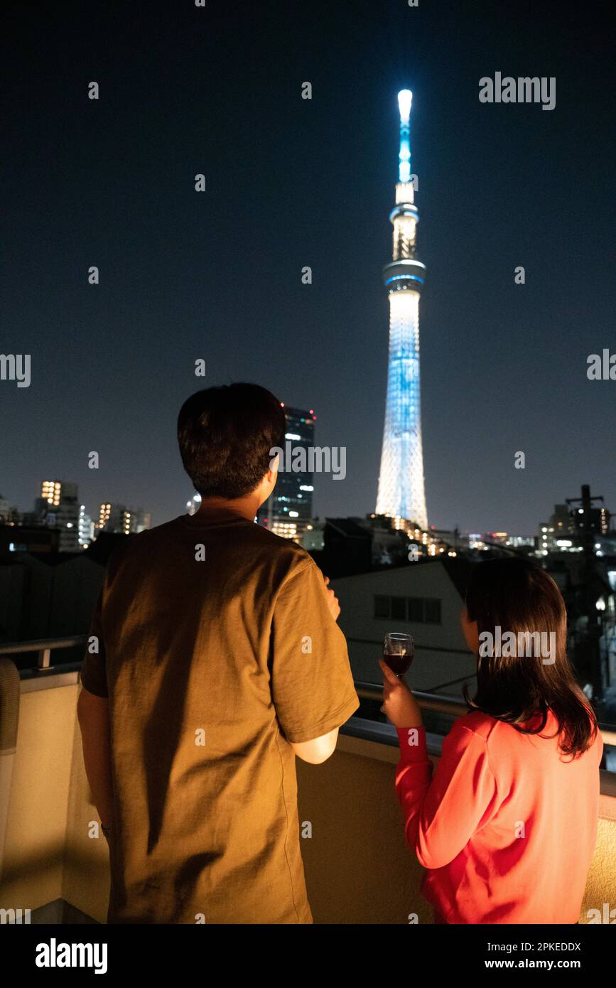 Ein Paar trinkt Wein auf dem Balkon, während man Sky Tree beobachtet Stockfoto