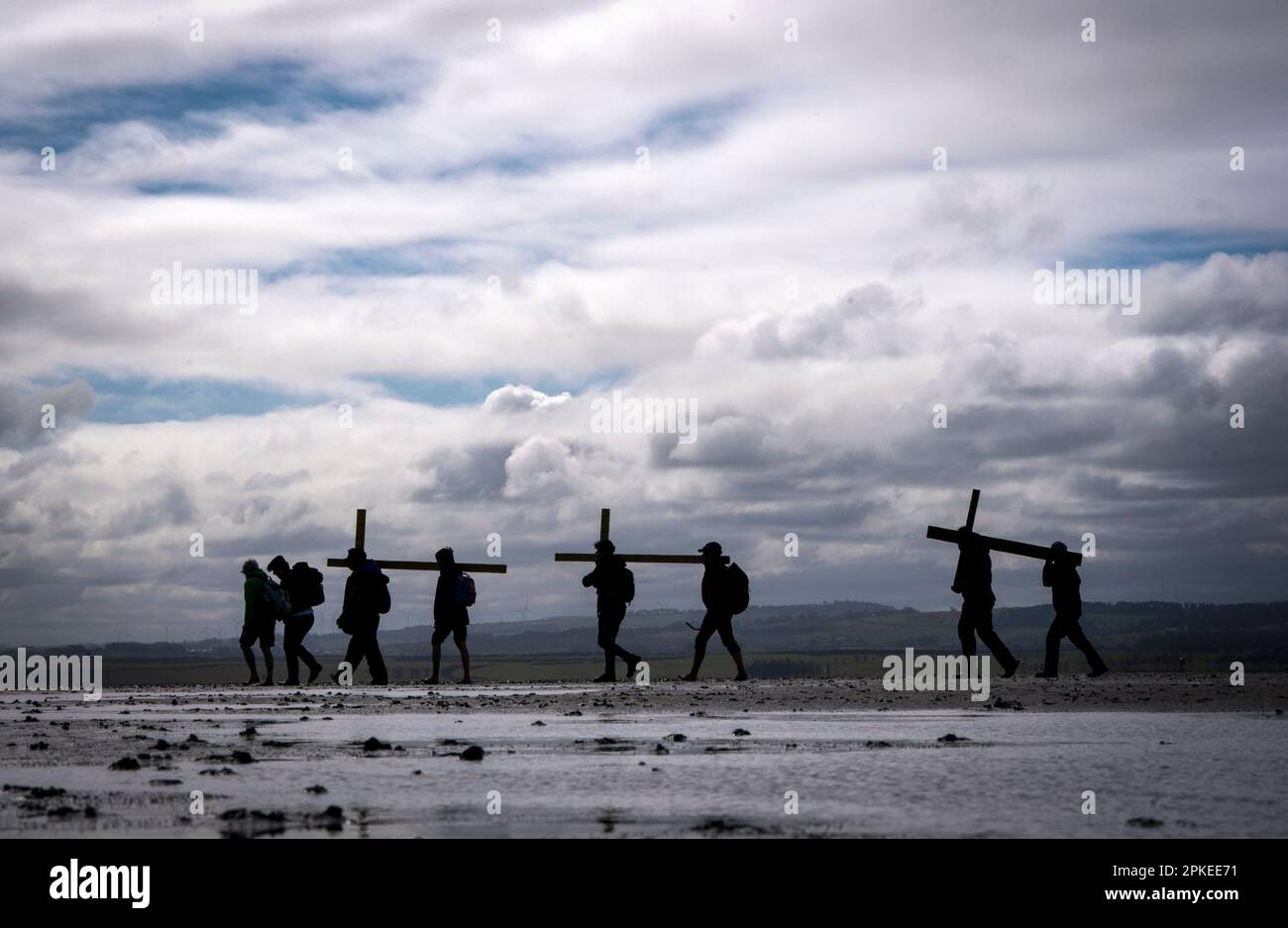 Pilger, die Kreuze zur Heiligen Insel Lindisfarne in Northumberland transportieren, während der jährlichen christlichen Osterpilgerfahrt am Karfreitag. Foto: Freitag, 7. April 2023. Stockfoto