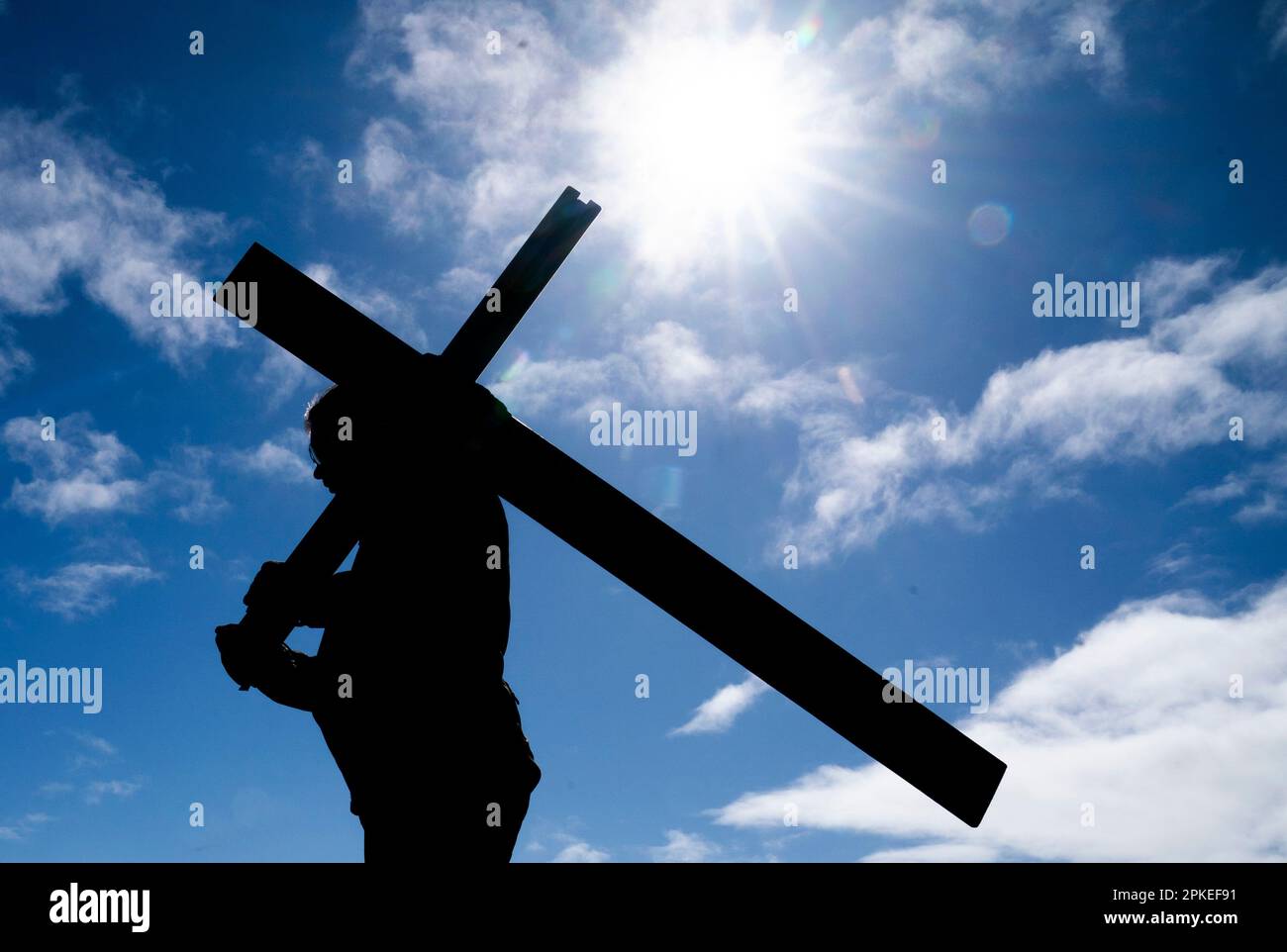 Ein Pilger trägt ein Kreuz am Anfang des Dammes zur Heiligen Insel Lindisfarne in Northumberland während der jährlichen christlichen Osterpilgerfahrt am Karfreitag. Foto: Freitag, 7. April 2023. Stockfoto