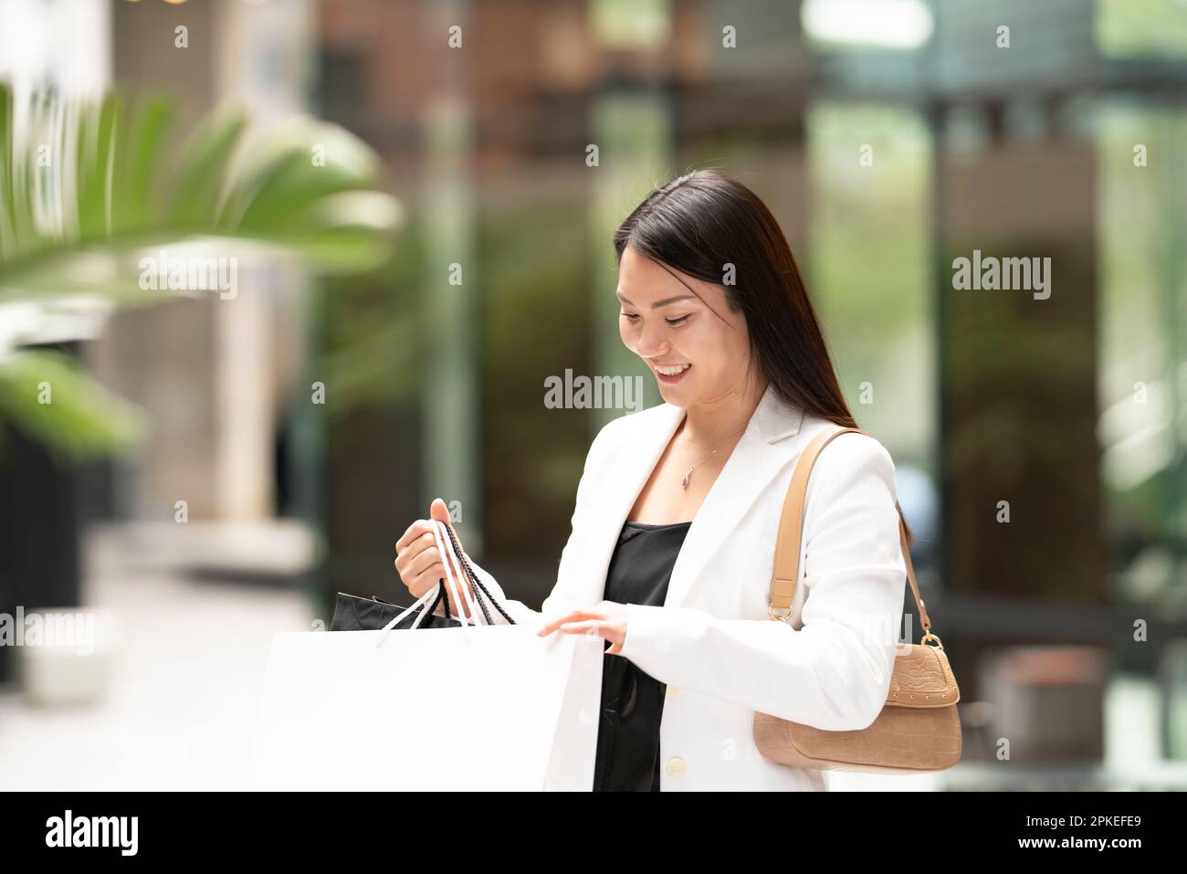 Eine Frau, die beim Einkaufen in eine Einkaufstasche guckt und ein Lächeln im Gesicht hat Stockfoto