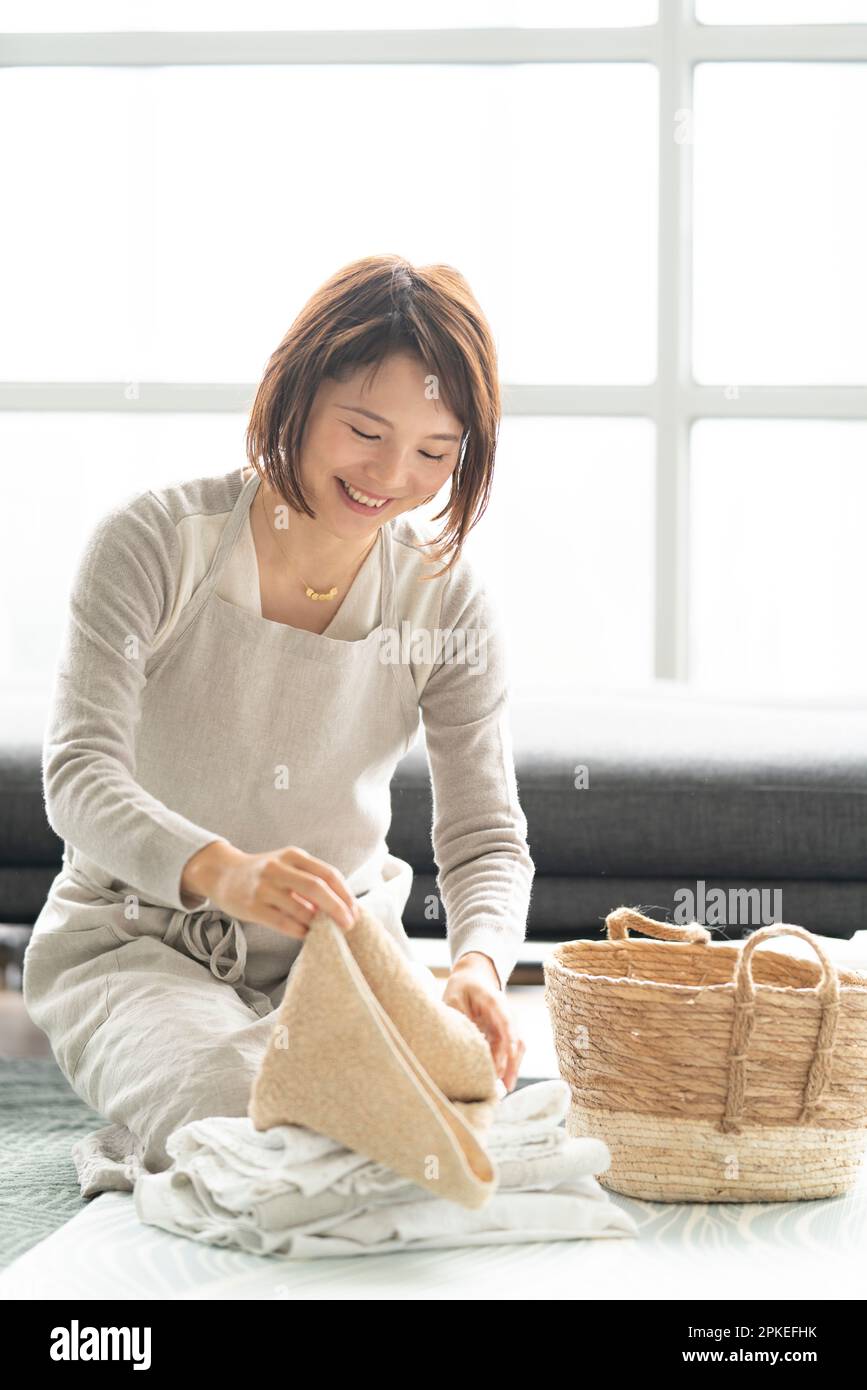 Eine Frau, die lacht, während sie Wäsche zusammenfaltet Stockfoto