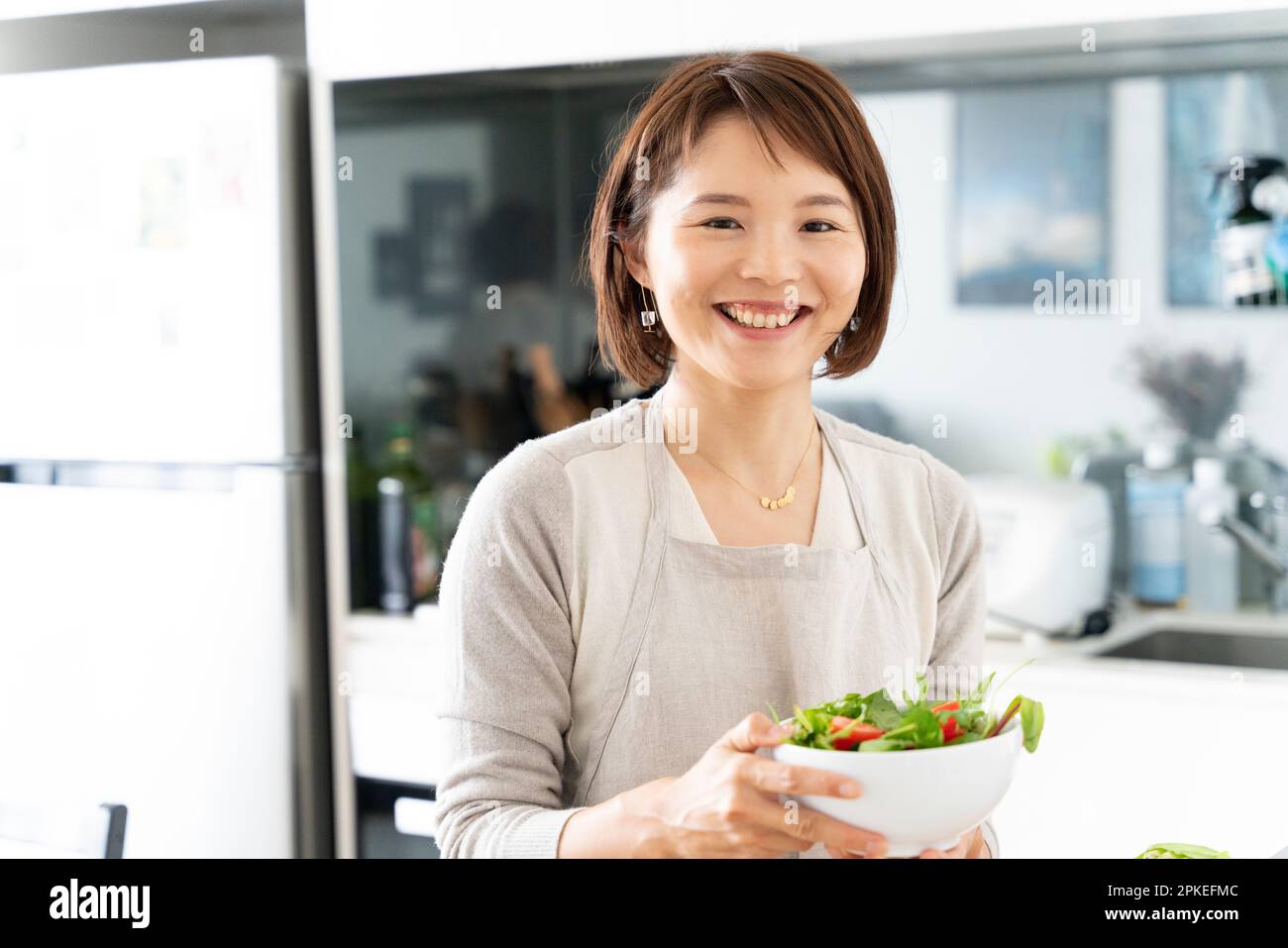 Frau in Schürze lacht mit Salat Stockfoto