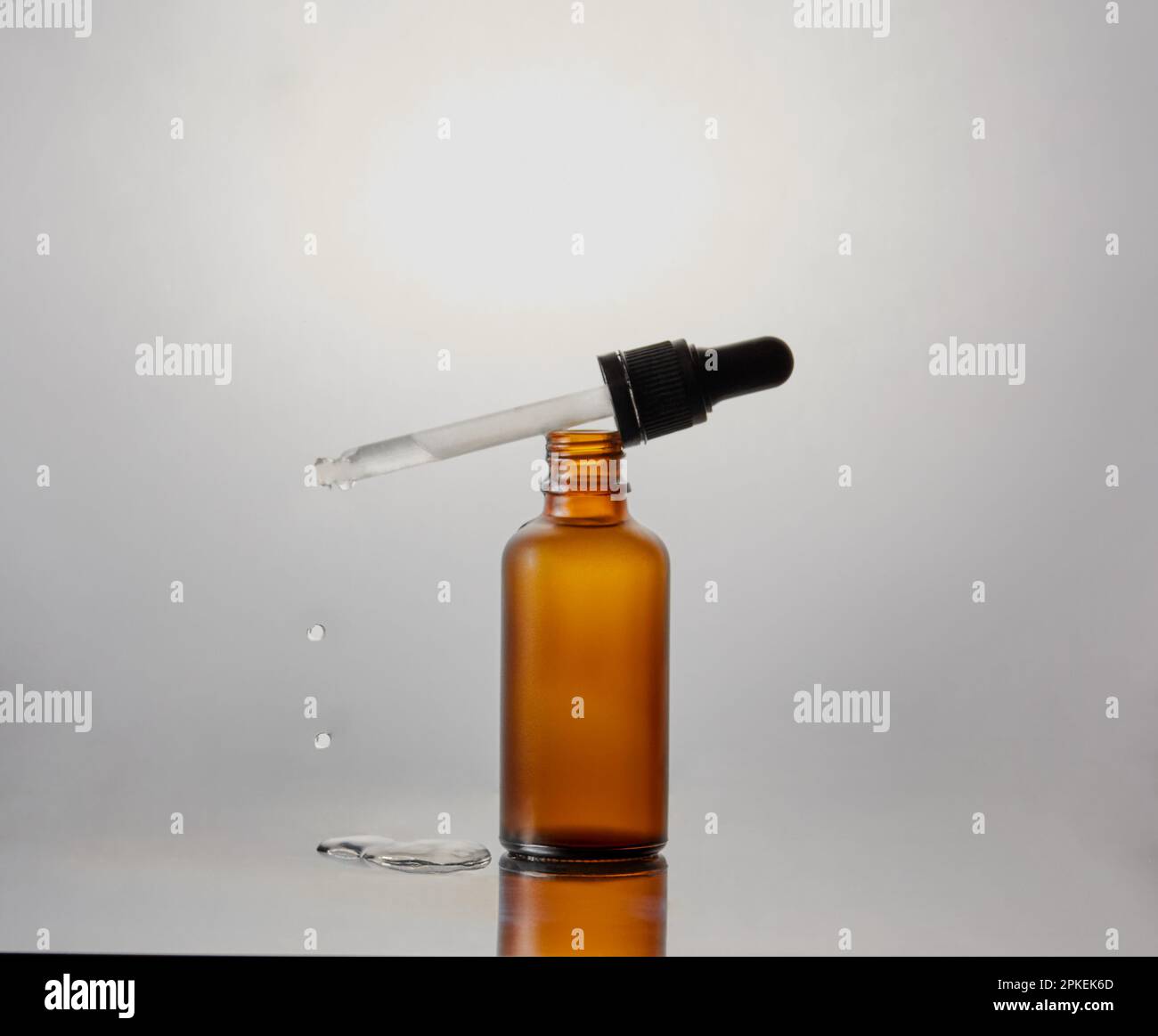 Flasche mit Flüssigkeit mit einer Pipette, Tropfer, der darauf liegt und Flüssigkeit herausfällt. Stockfoto