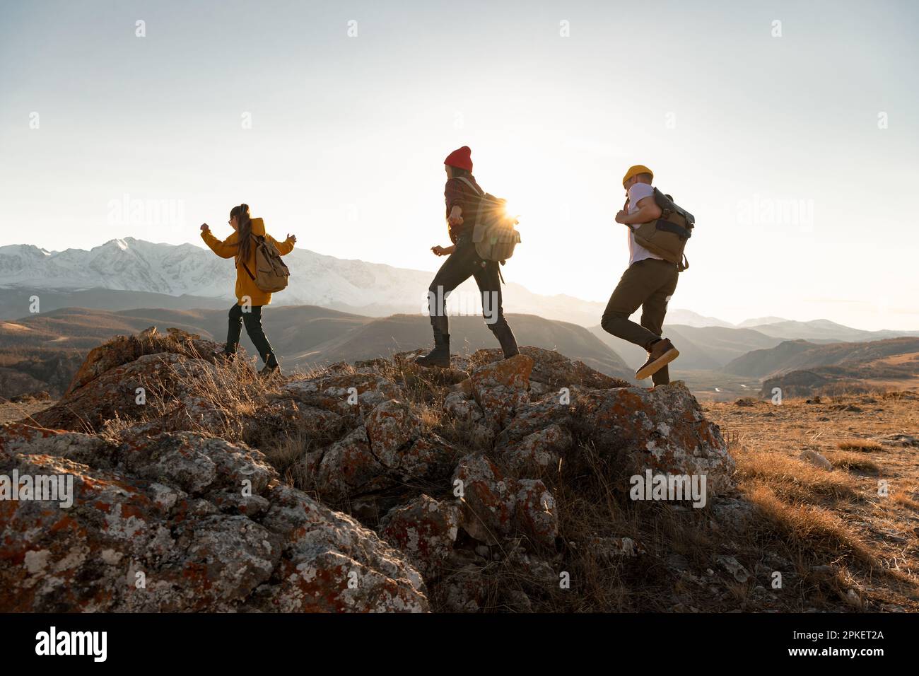 Eine Gruppe junger Wanderer wandert bei Sonnenuntergang in den Bergen. Silhouetten von Wandertouristen mit Rucksäcken Stockfoto