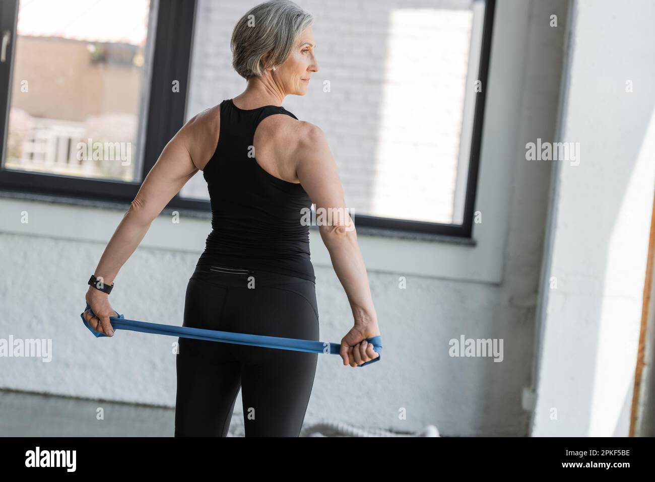 Fit Seniorin trainiert mit Widerstandsband im Sportzentrum, Börsenbild Stockfoto