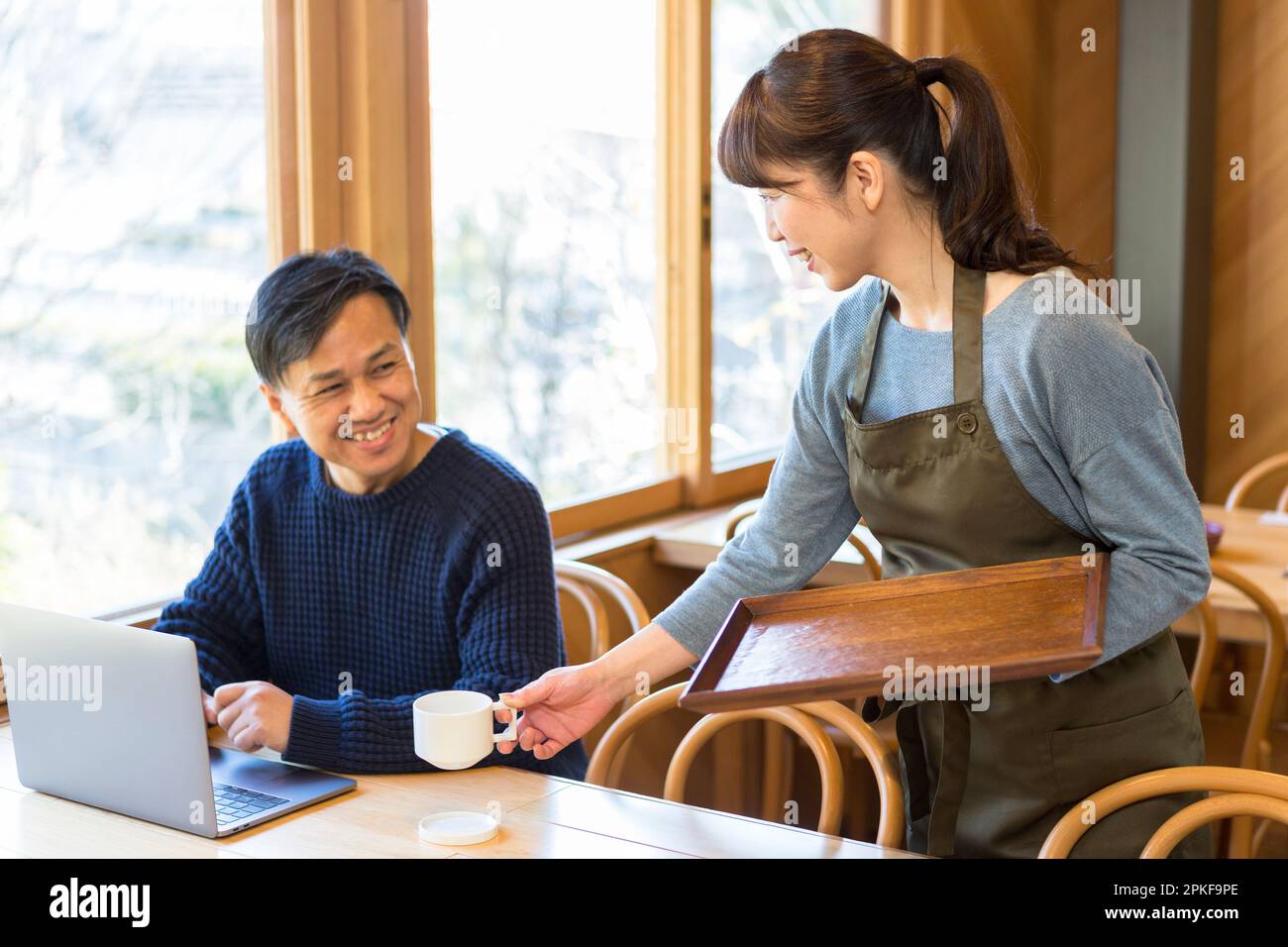 Weibliche Kellnerin, die einem männlichen Gast Kaffee serviert Stockfoto