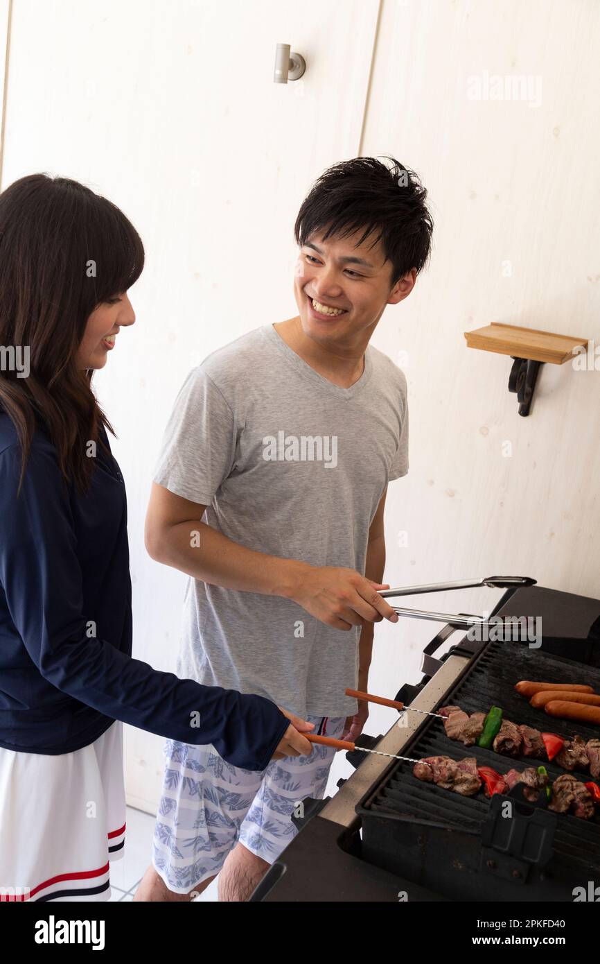 Ein junges Paar grillt Fleisch auf dem Grill Stockfoto