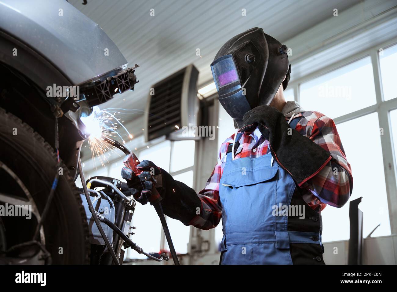 Schweißer in einer Schweißmaske arbeitet in der Autoherstellung Stockfoto