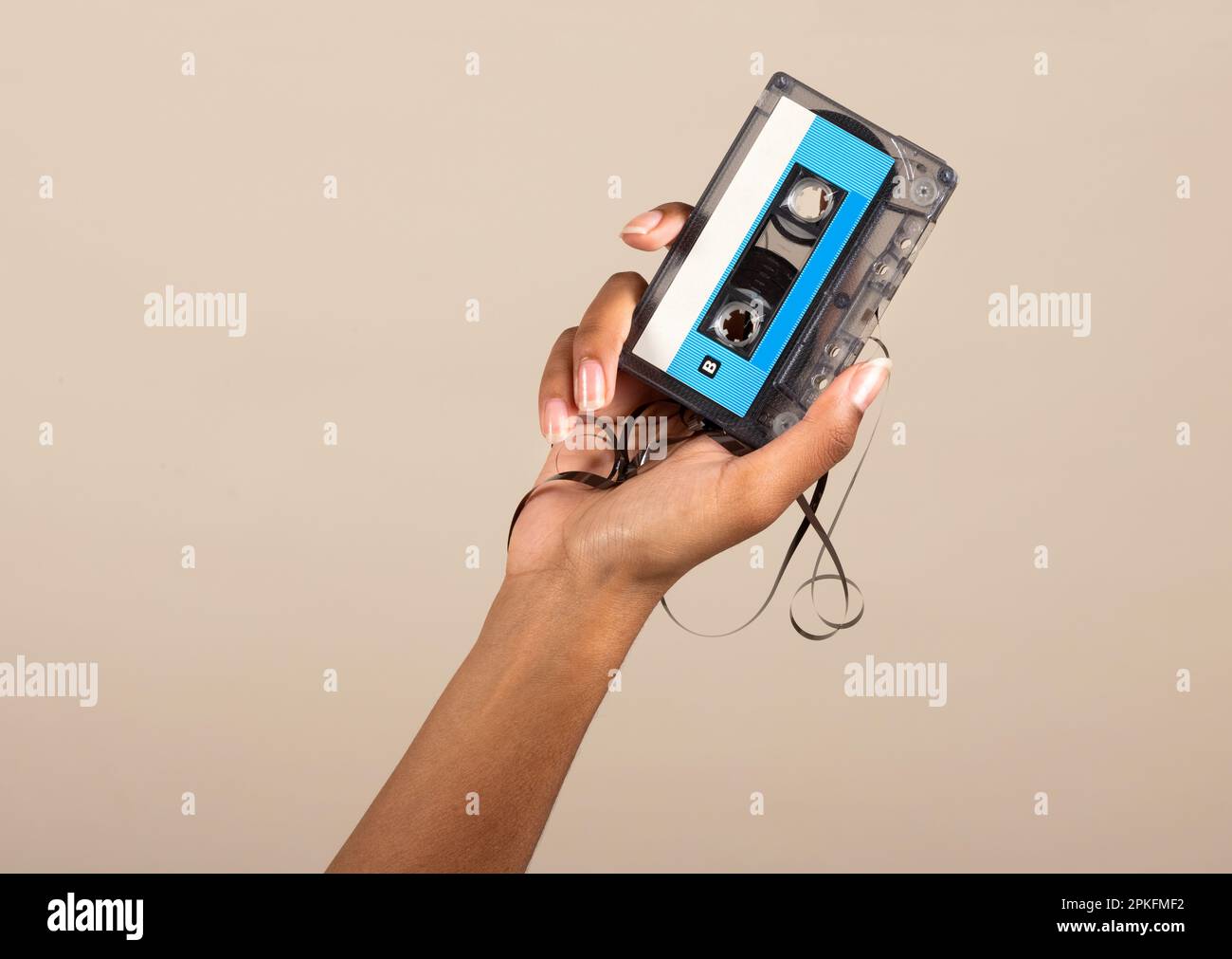 Anonyme afroamerikanische weibliche Hand zeigt klassische Audiokassetten auf beigem Hintergrund Stockfoto