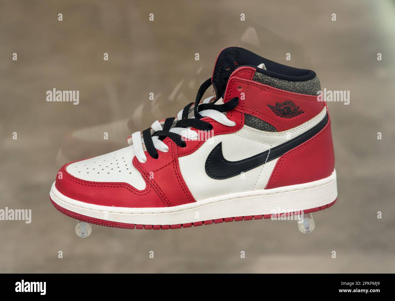 Trendiger Nike Air Jordan Sneaker in Rot, Weiß und Schwarz auf verschwommenem grauem Hintergrund Stockfoto