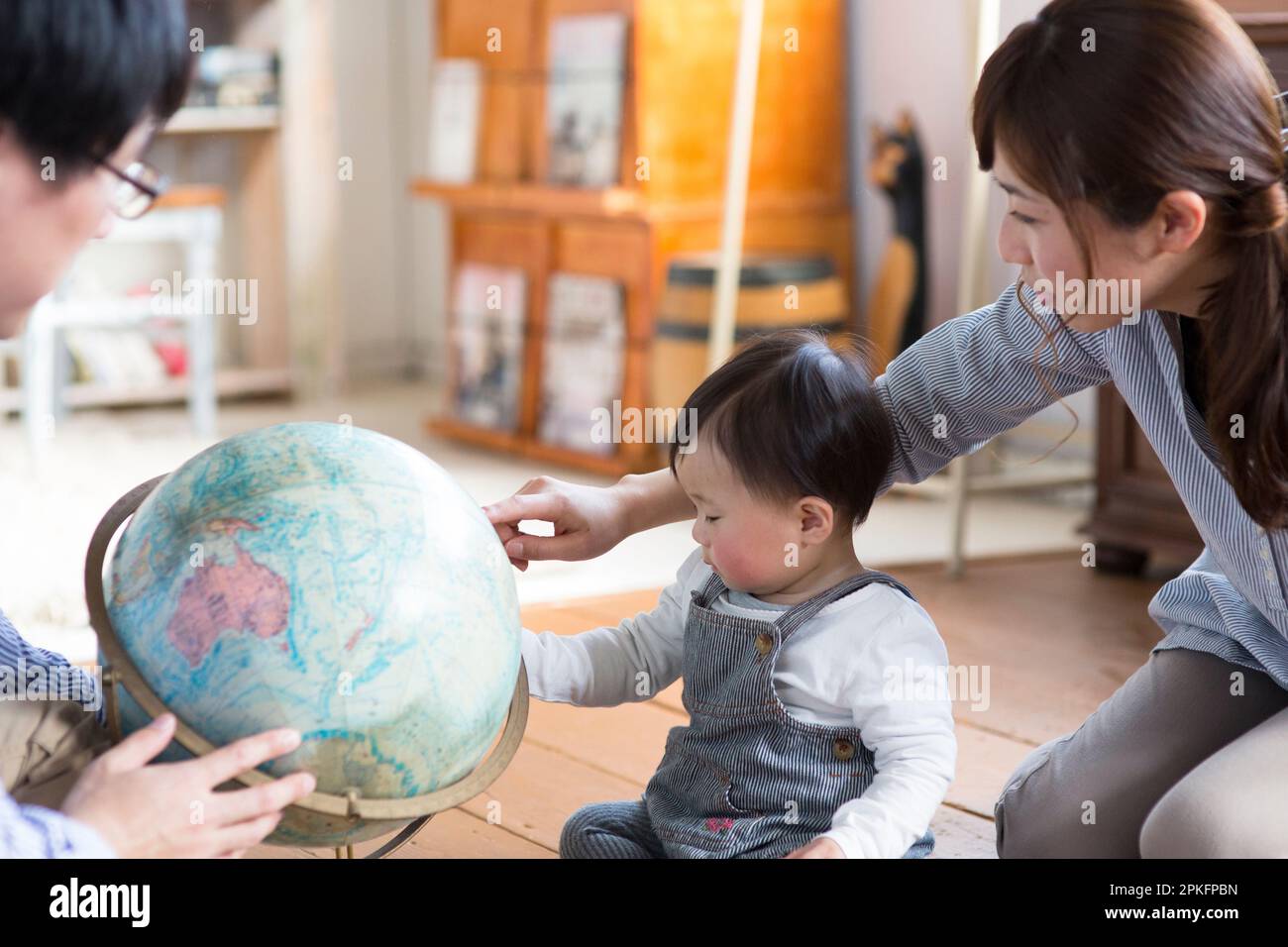 Baby und Eltern spielen mit einem Globus Stockfoto