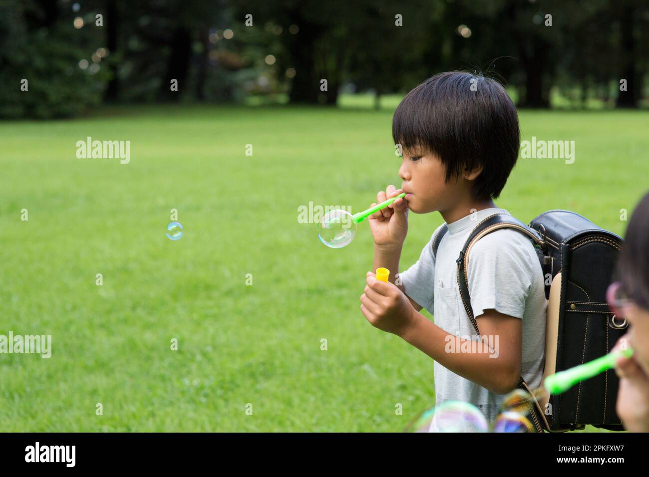 Ein Grundschüler, der mit Seifenblasen spielt Stockfoto