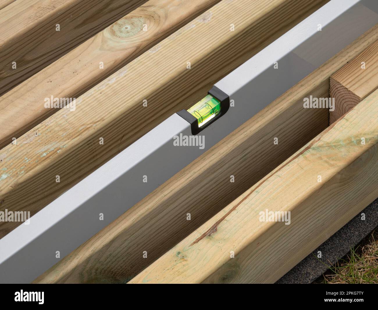 Wasserwaage die Wasserwaage einer Holzbohle prüfen. Nahaufnahme. Stockfoto