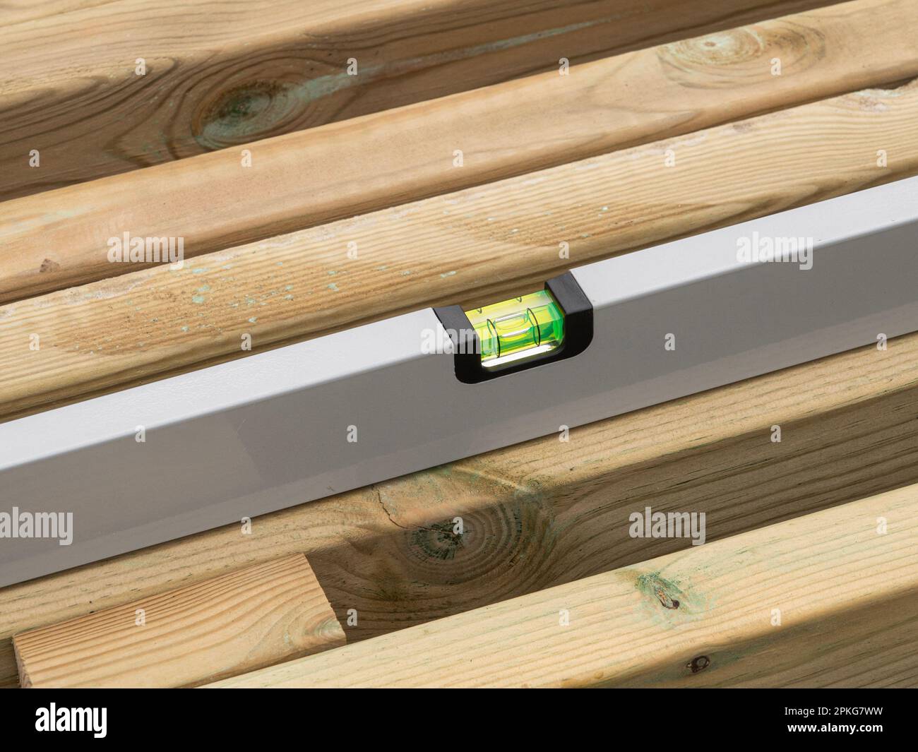 Wasserwaage die Wasserwaage einer Holzbohle prüfen. Nahaufnahme. Stockfoto