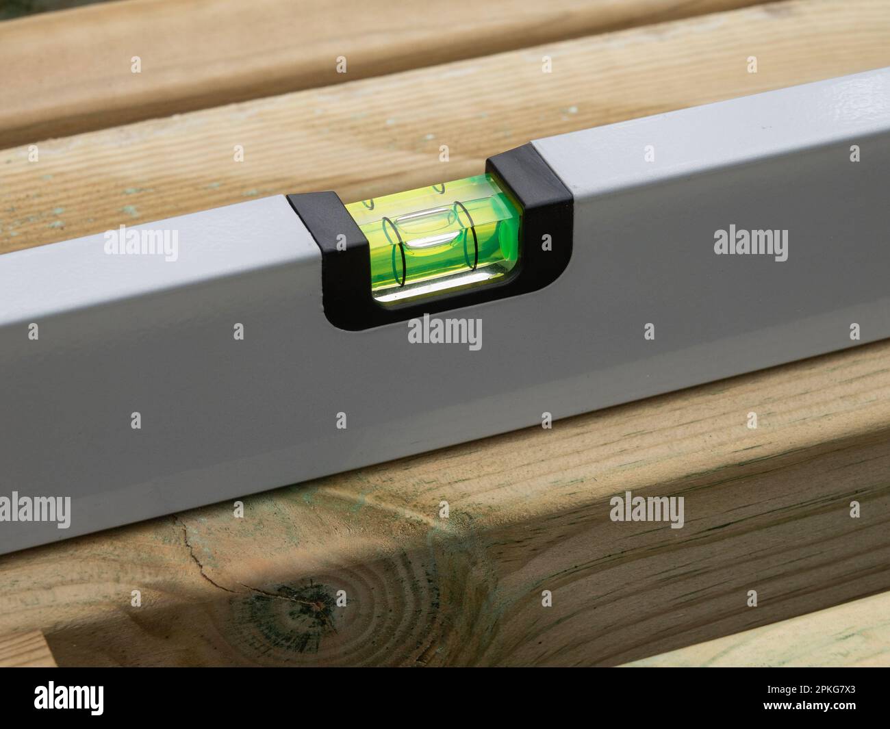 Wasserwaage die Wasserwaage einer Holzbohle prüfen. Nahaufnahme. Stockfoto