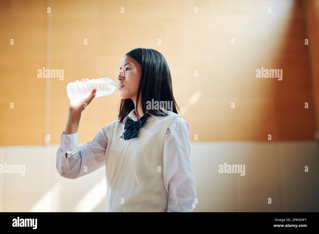 Highschool-Mädchen trinken Wasser im Fitnessstudio Stockfoto