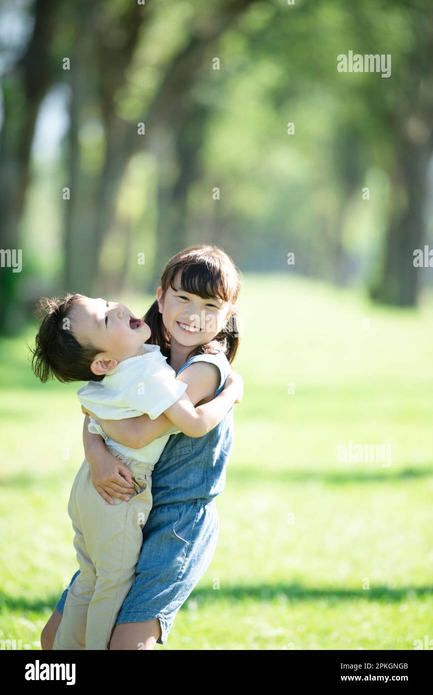 Eine Schwester und ein Bruder umarmen sich in einer Reihe von Pappelbäumen Stockfoto