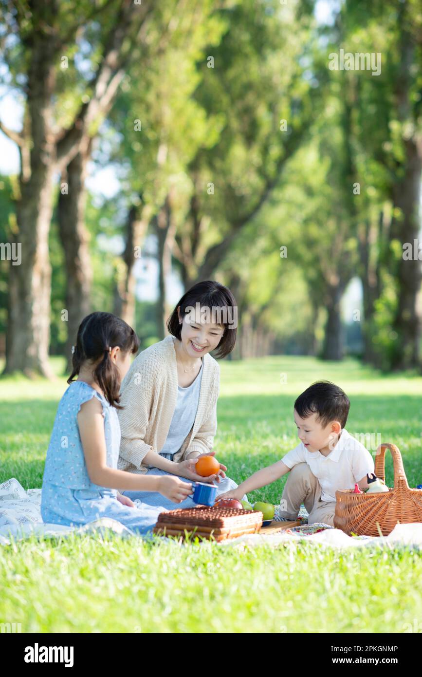 Eltern und Kinder machen ein Picknick an einer Reihe von Pappelbäumen Stockfoto