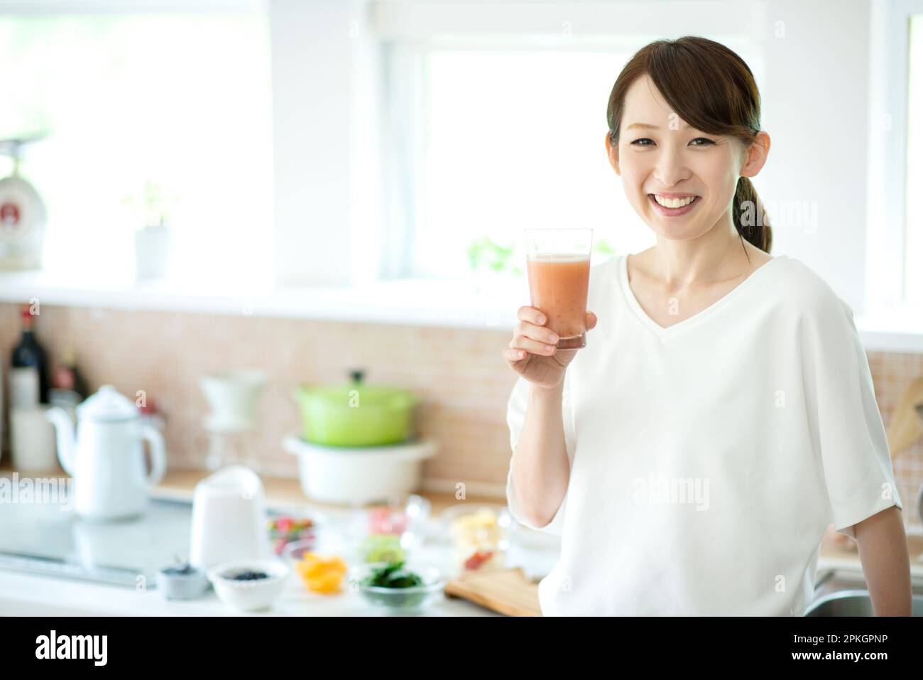 Lächelnde Frau Mit Smoothie In Der Küche Stockfoto