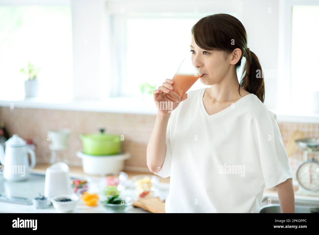 Eine Frau, Die Smoothie In Der Küche Trinkt Stockfoto
