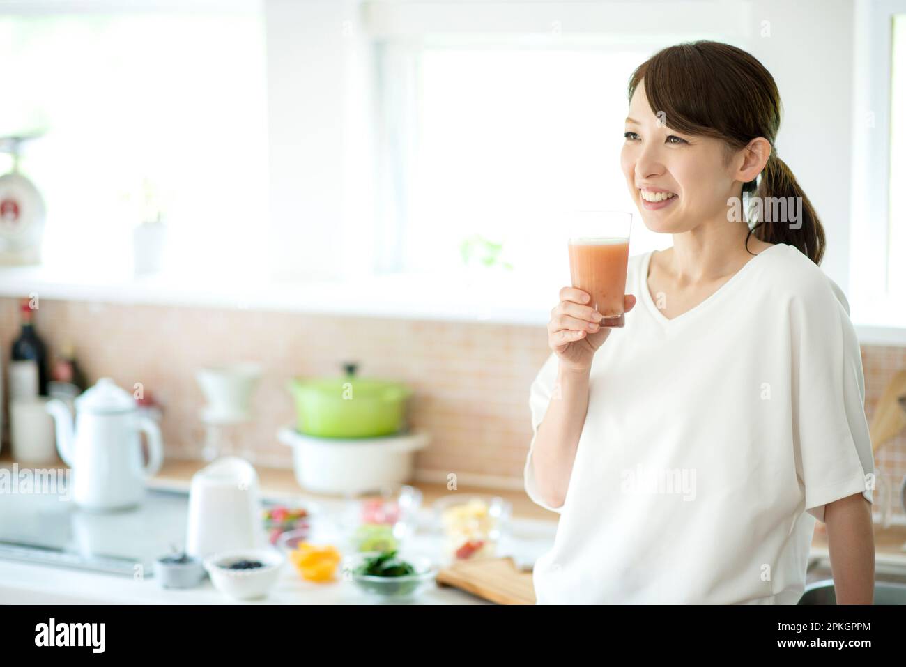 Lächelnde Frau mit Smoothie in der Küche Stockfoto