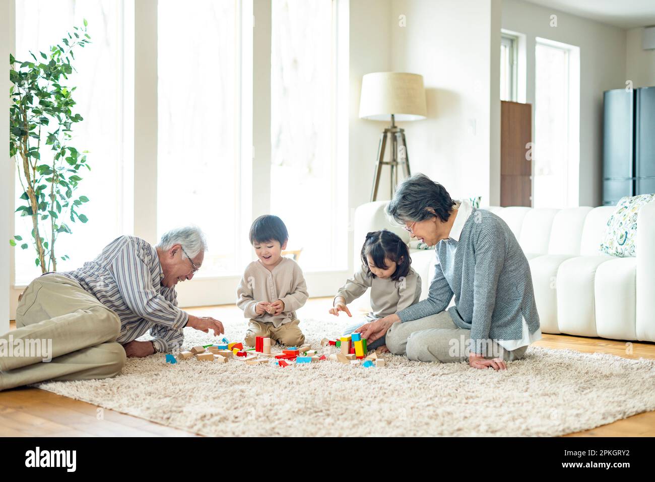 Großeltern und Enkel, die mit Bausteinen spielen Stockfoto