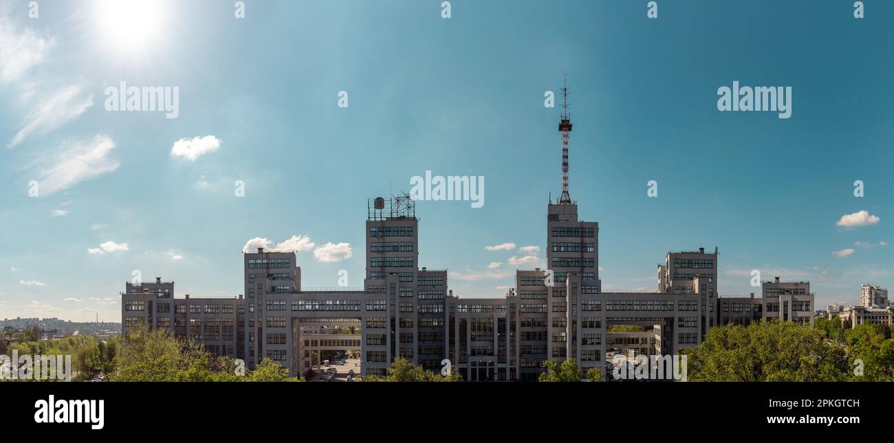 Panoramablick auf das Derzhprom-Gebäude mit blauem Himmel und grünen Bäumen im Frühling im Zentrum von Charkiv, Ukraine. Konstruktivistischer Architekturstil Stockfoto