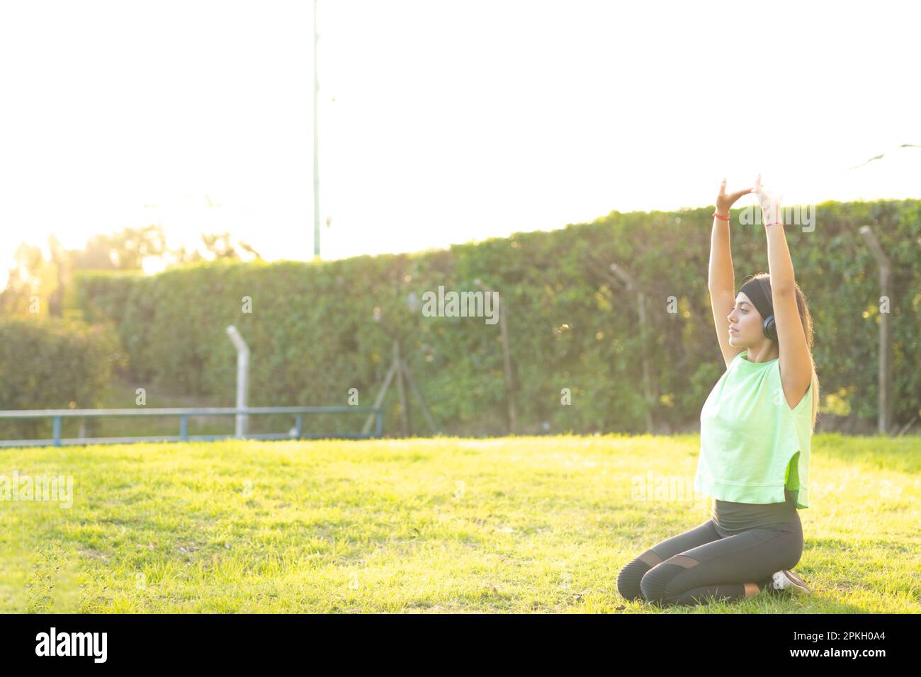 Ein Teenager, das Yoga übt, Arme hebt und auf den Füßen sitzt Stockfoto